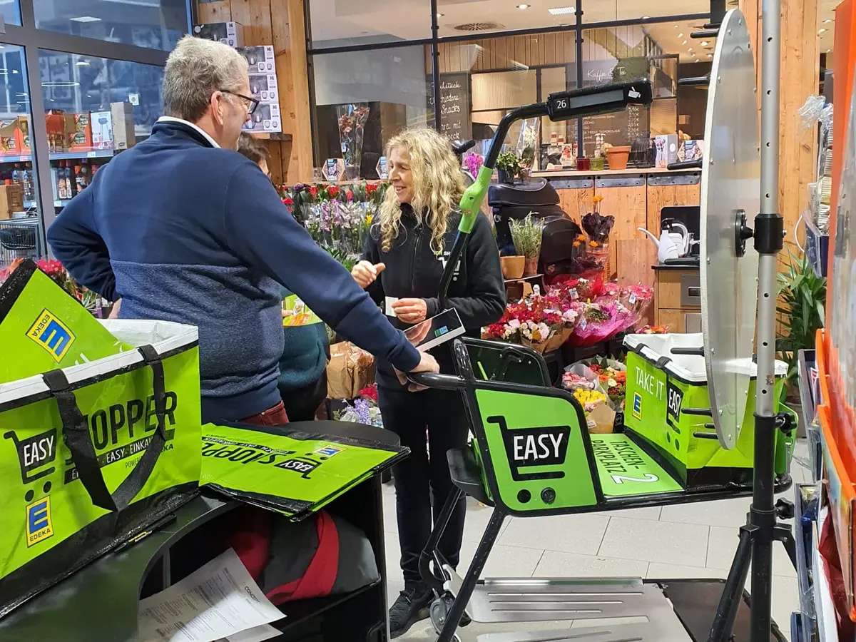 Mitarbeiterin erklärt einem Kunden den Easy Shopper